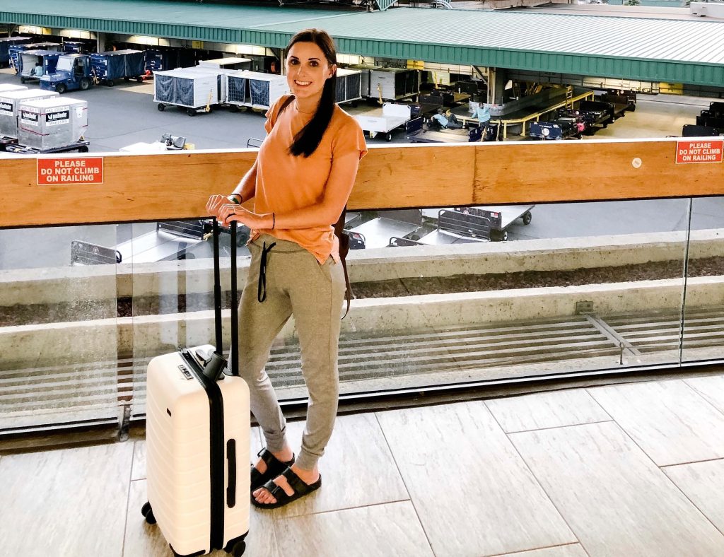 Girl with pink suitcase - traveling carry-on only is the best way to travel