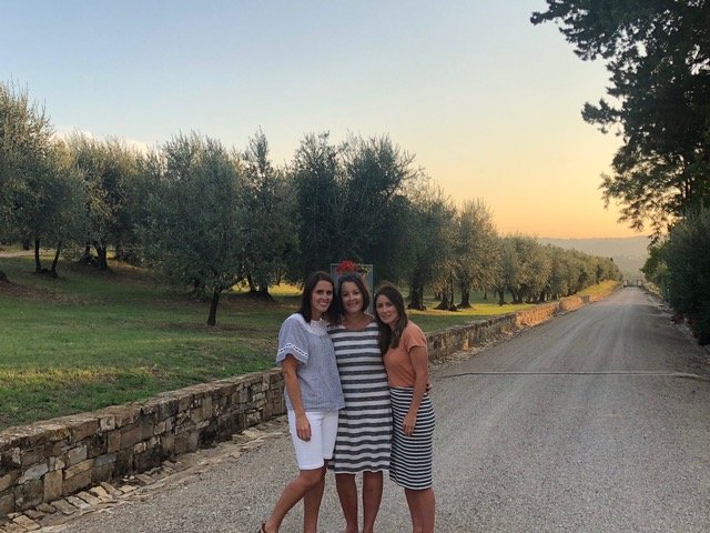 Three women standing by olive trees in Italy enjoying a girls trip