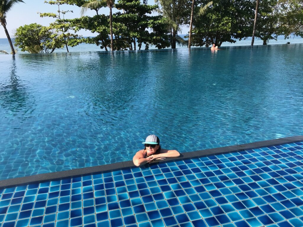 Woman at pool edge with baseball hat.