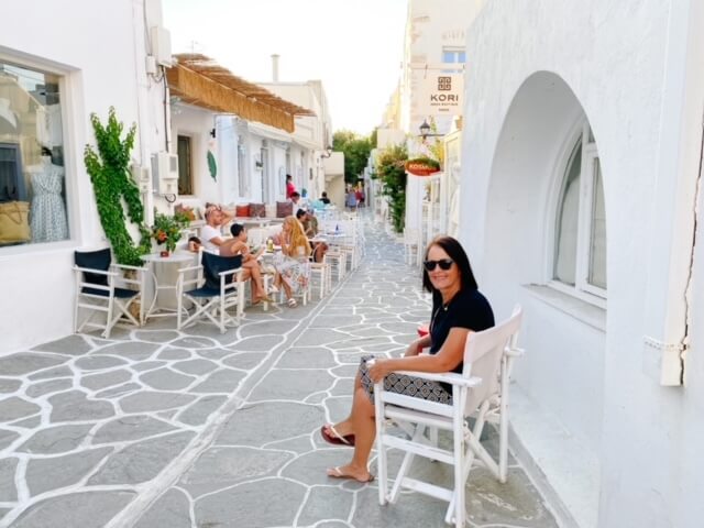 Woman sitting in white chair near white buildings