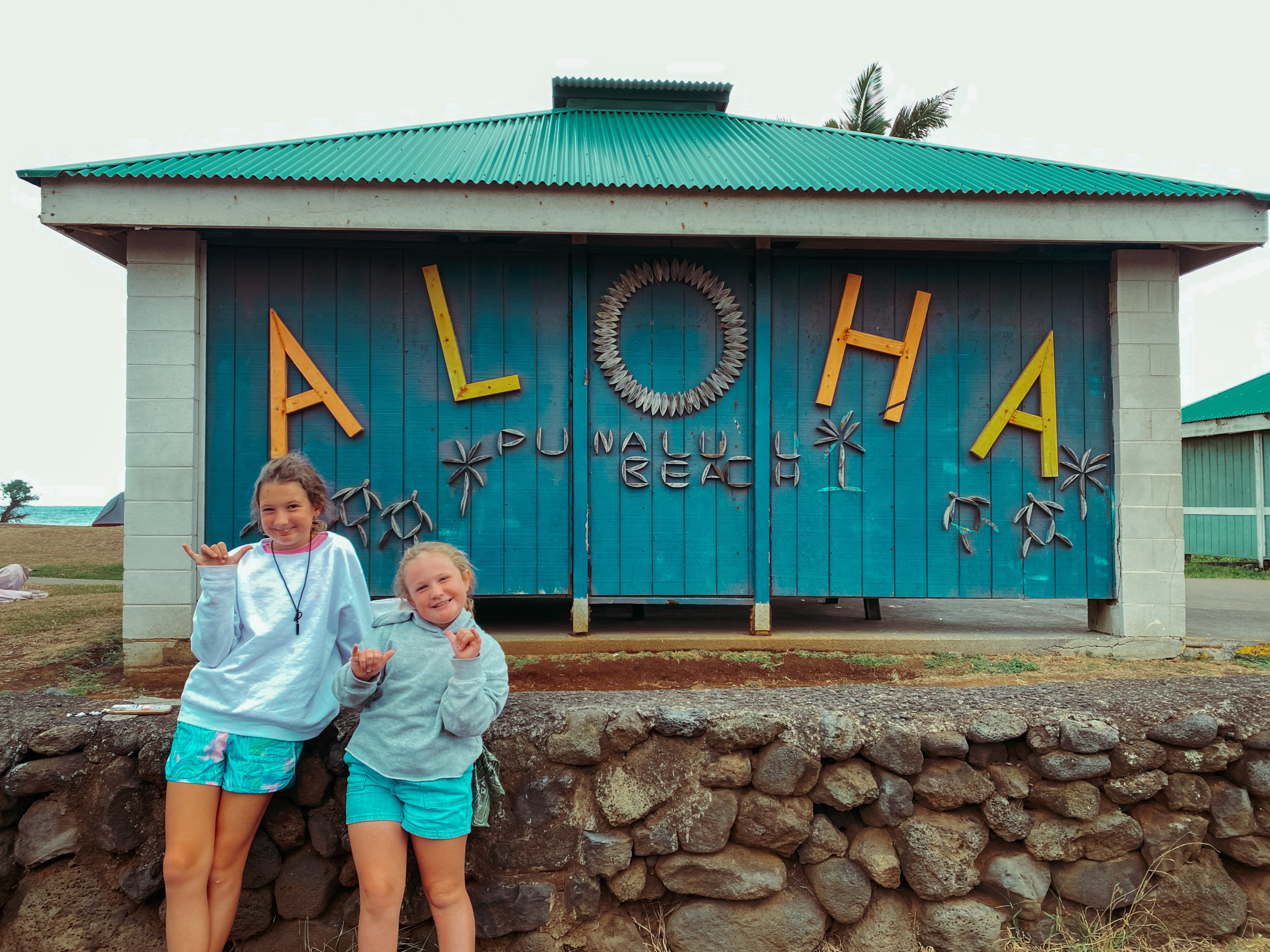 2 young girls by large blue Aloha sign
