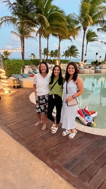 Three woman standing near pool.