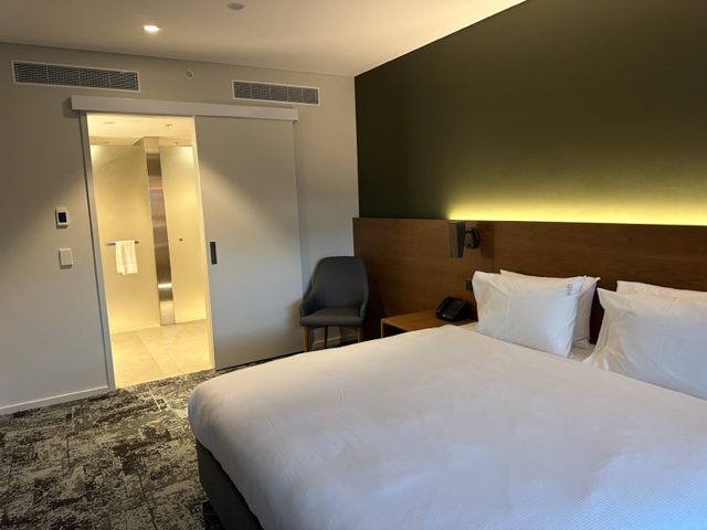 Hotel room with green back wall, white comgforter