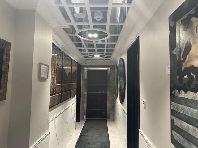 Hallway in hotel with glass ceiling, black doors