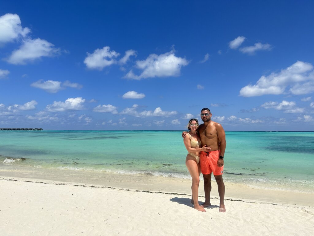 Man and woman in bathing suits standing on white sand beach