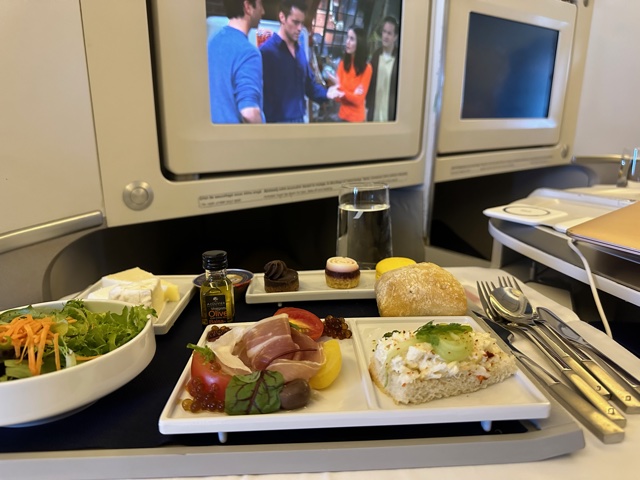Food tray on plane in front of tv screen.