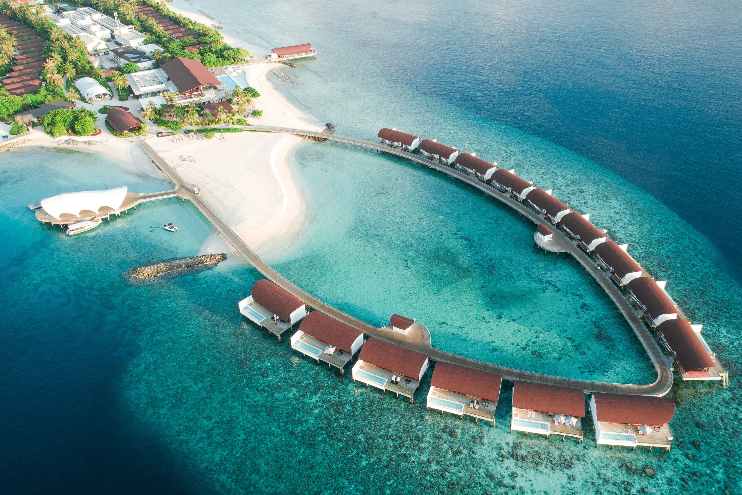 Overwater bungalows over turquoise water near island.