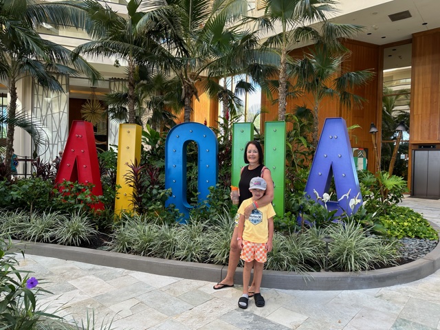 Woman and child standing near Aloha sign