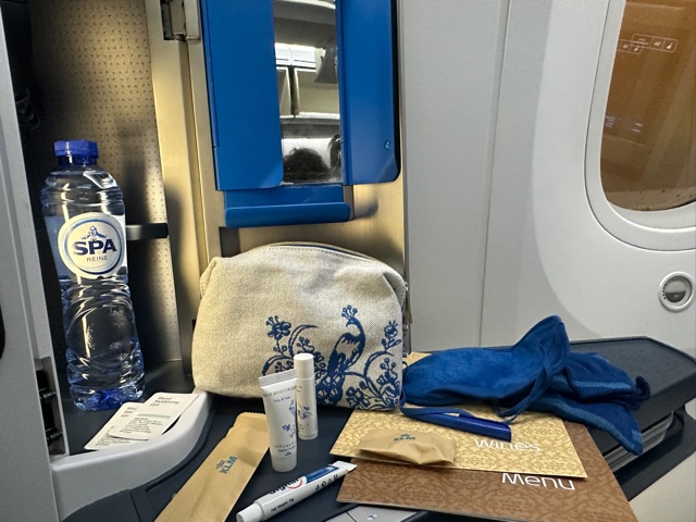 Small cupboard on plane with mirror, water and toiletries.