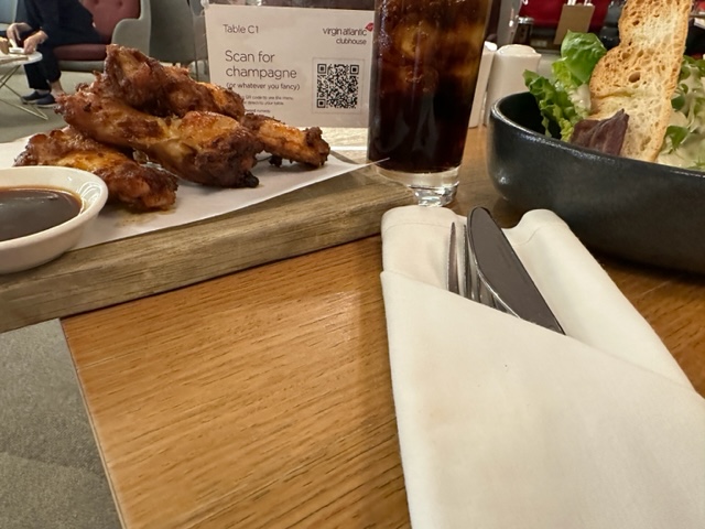 Chicken wings, salad, and brown drinks on table