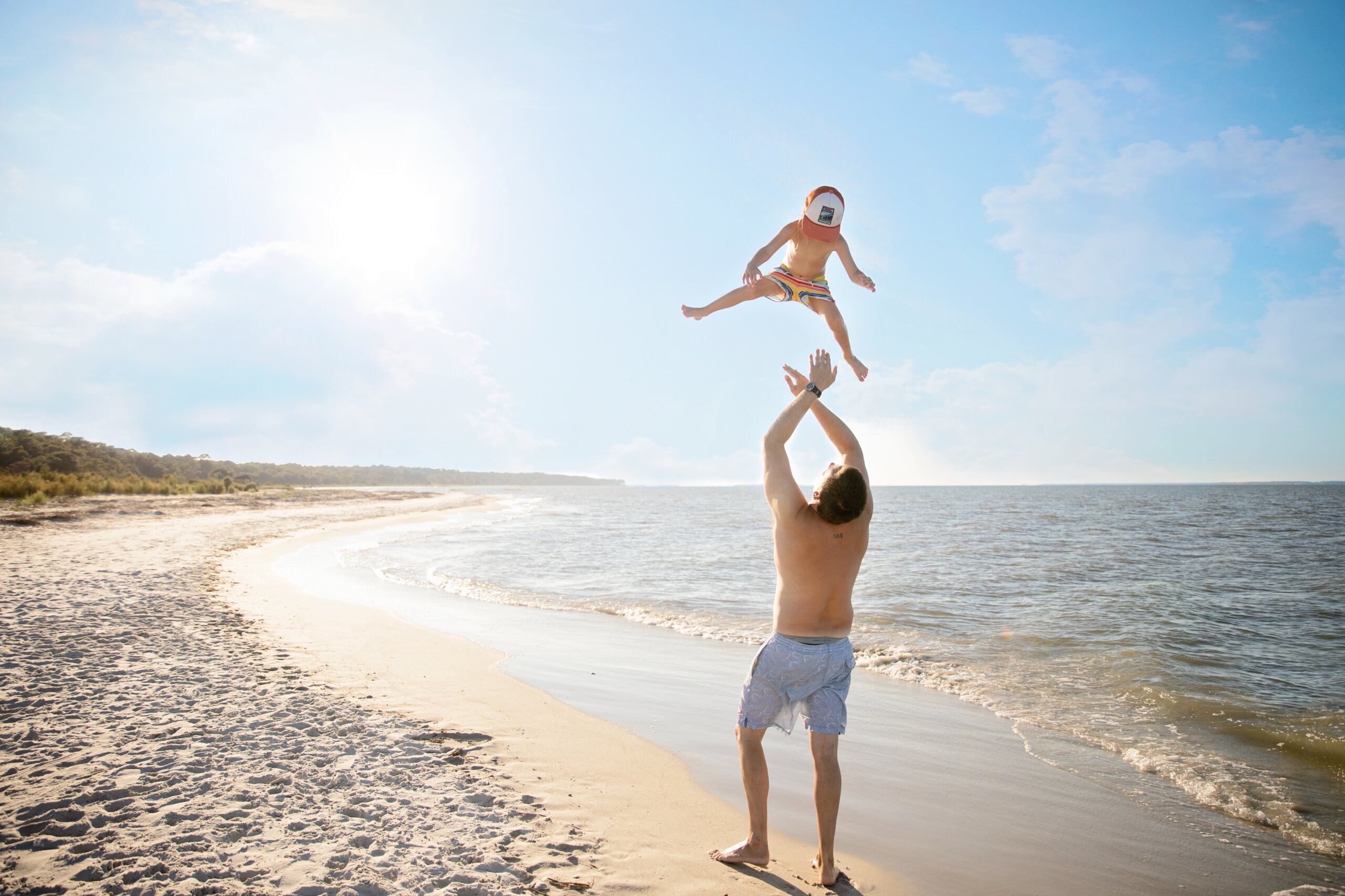 Man throwing child in air near beach