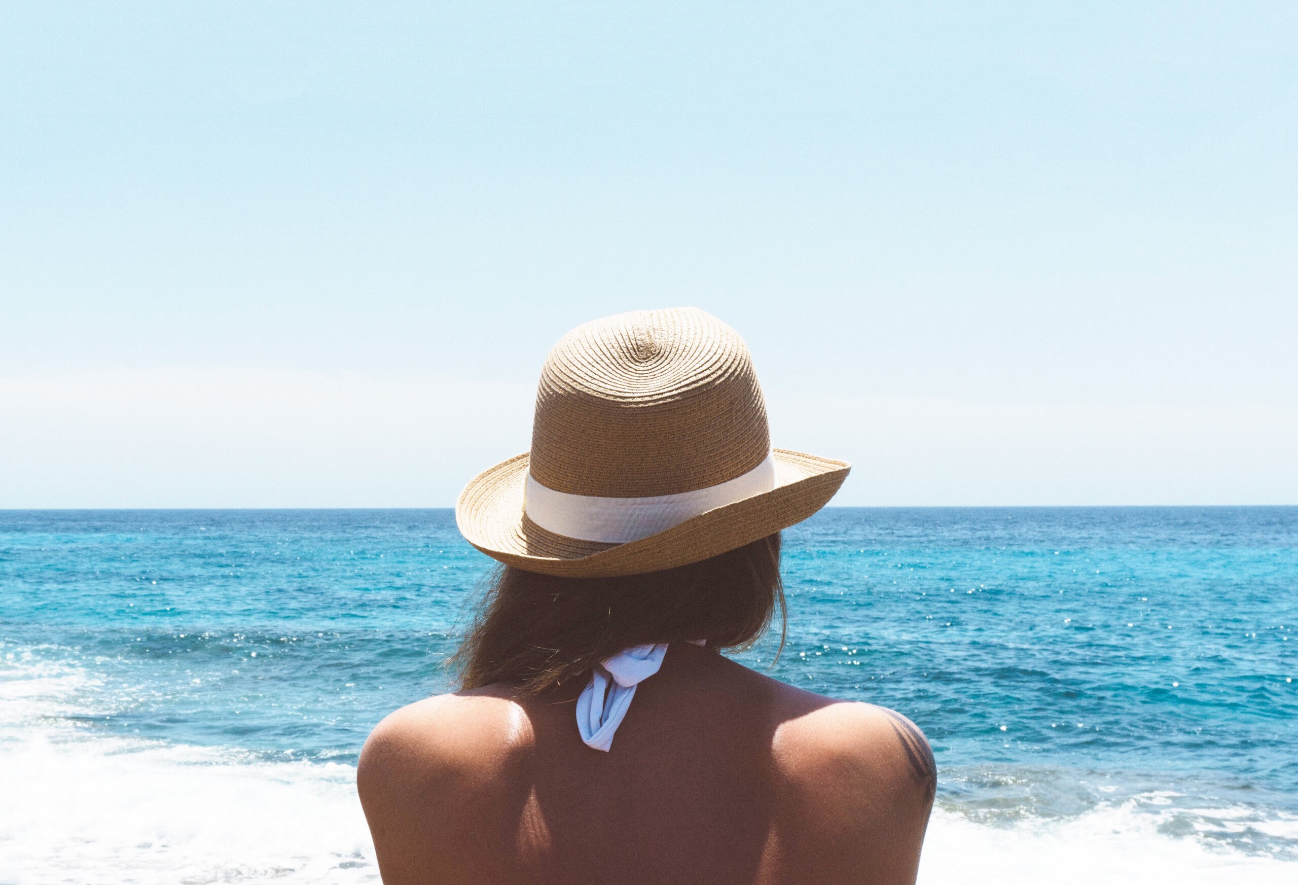 Back of woman's head with hat on at beach
