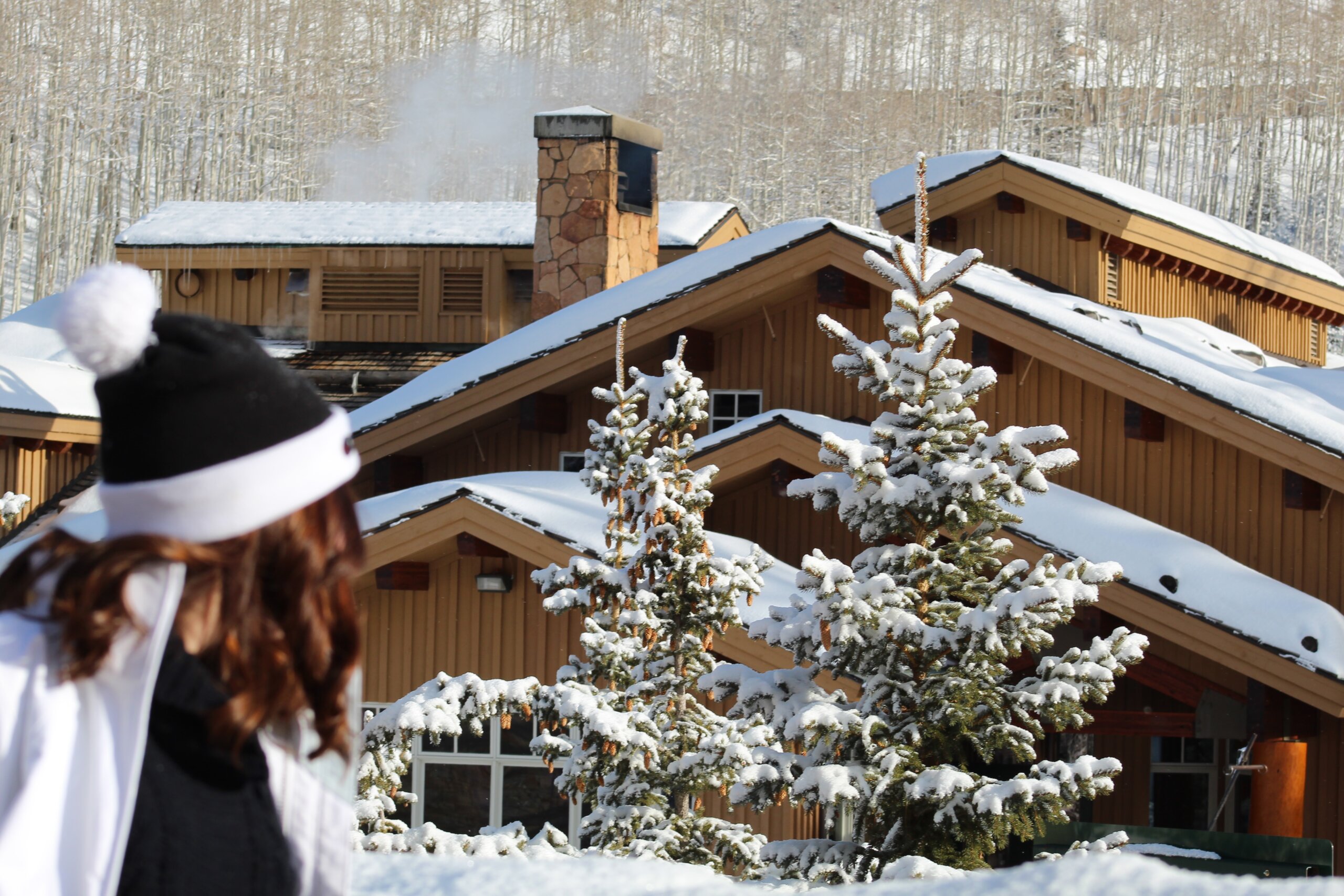 Woman standing in front of snow covered trees and ski lodge