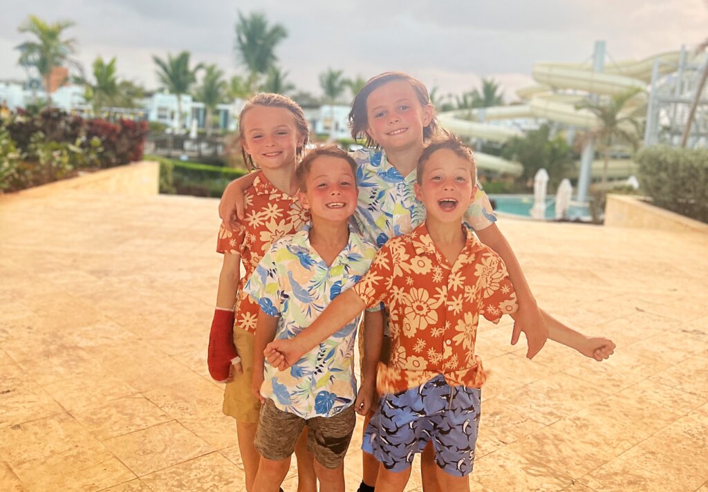 Four boys dressed in flowered shirts standing on beach on Family Vacation to Punta Cana