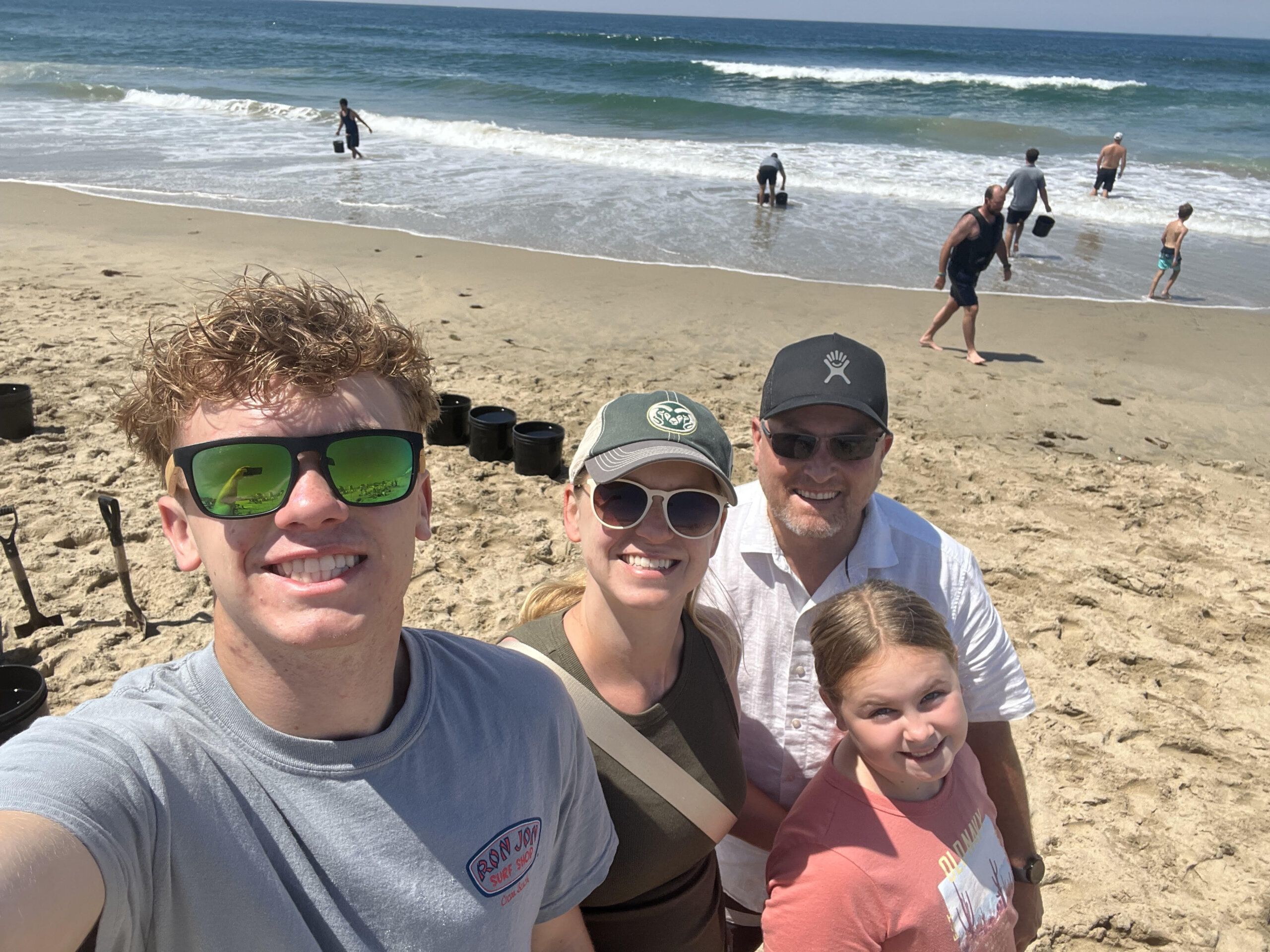 Family of four on the beach near an ocean.