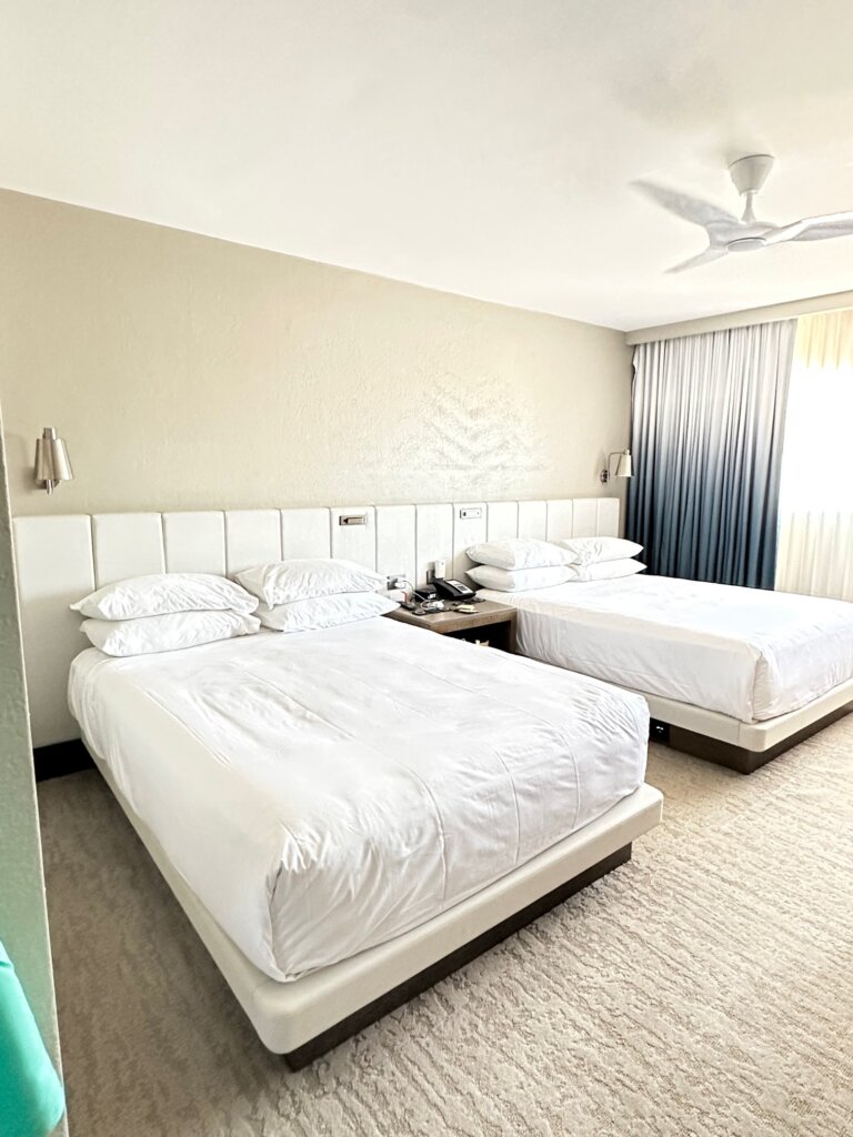Hotel room with 2 white beds - Reader Success Story to Aruba