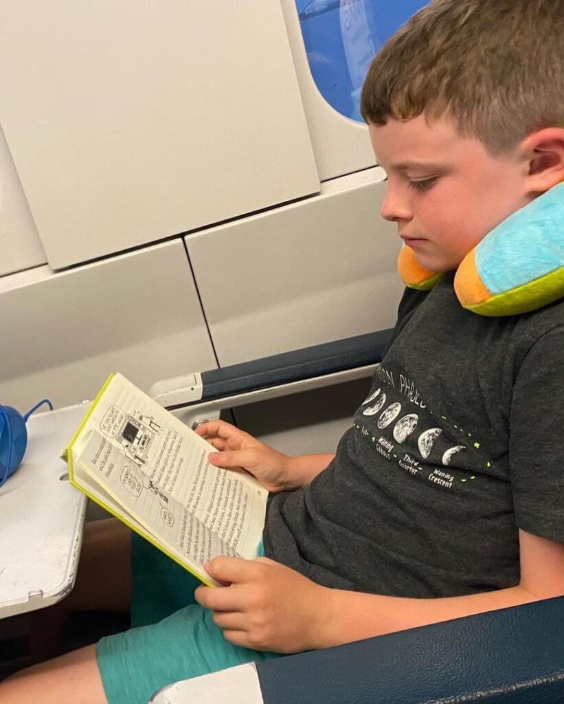 Reader success story to Spain: Boy on airplane, reading book. 