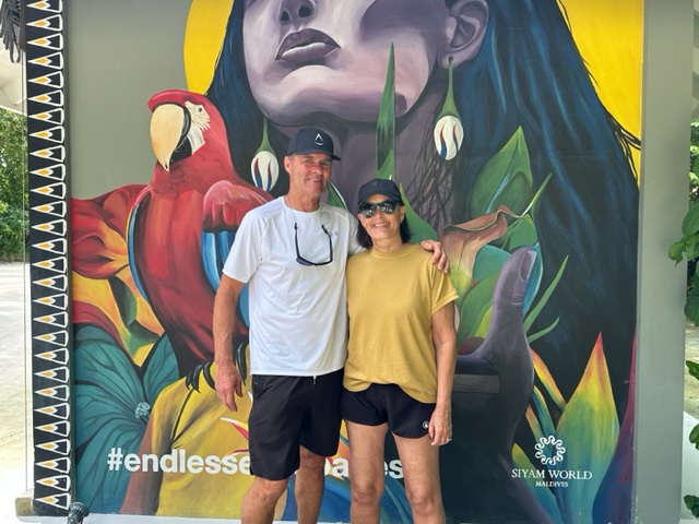 Man and woman standing by colorful mural - Mixing Points and Miles with Cash for a Maldives Trip