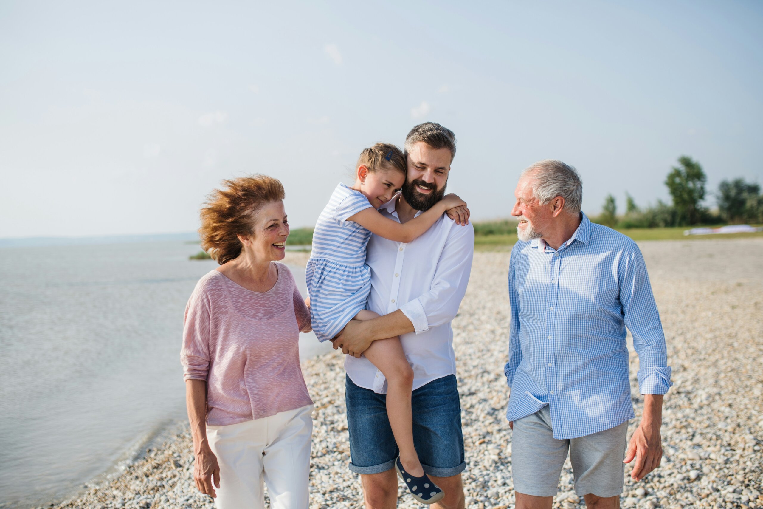 Older woman and man with young man holding child at beach