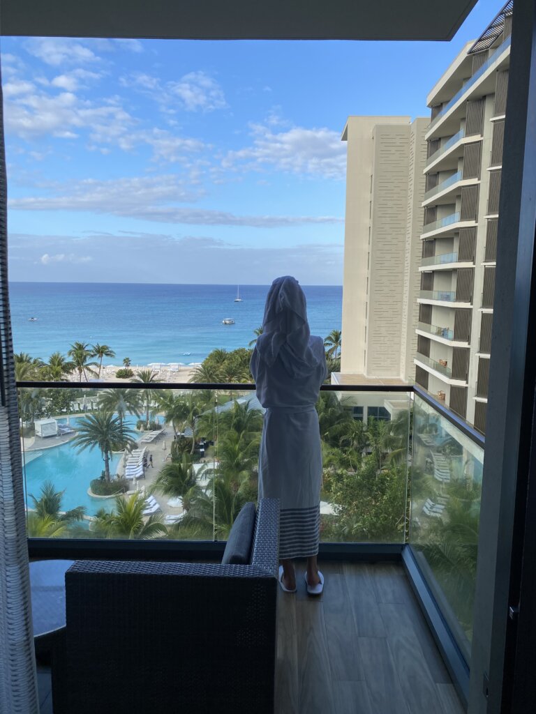 Woman on balcony of hotel looking at ocean view