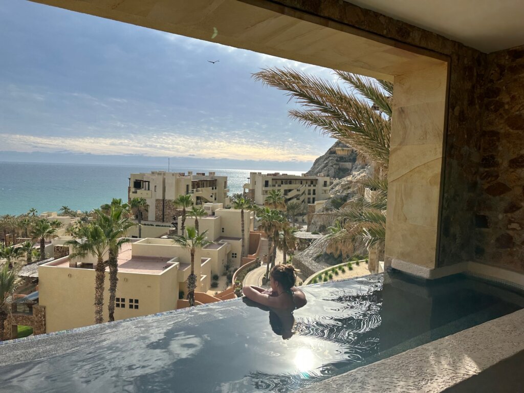Girl in plunge pool at hotel with ocean view.