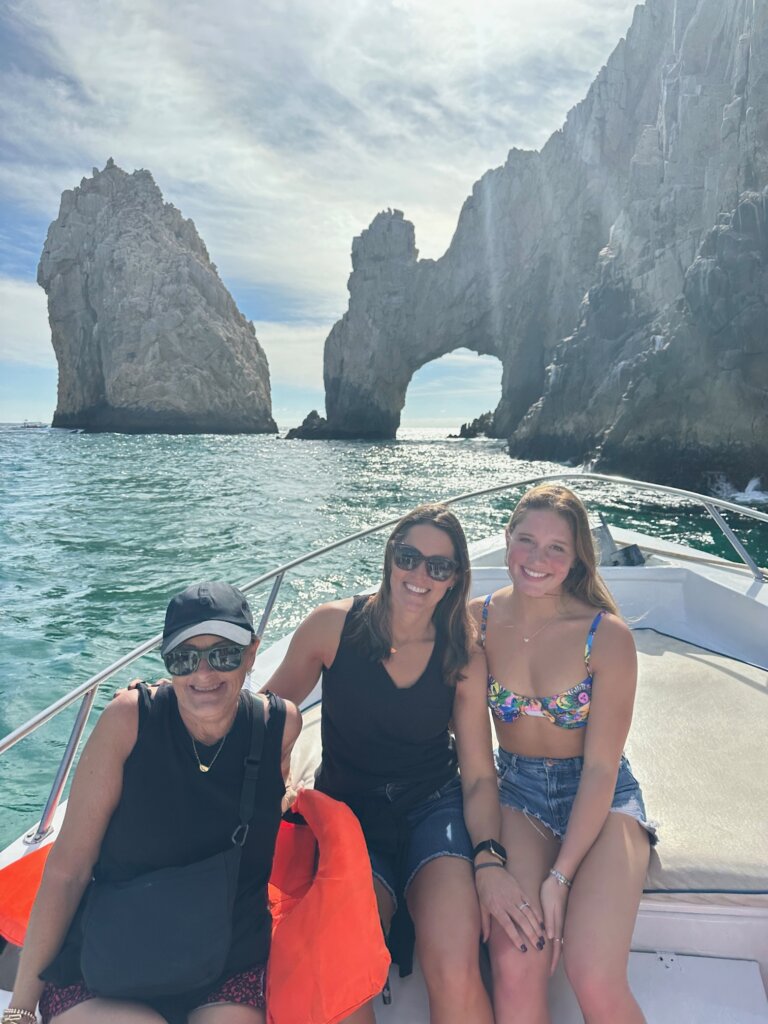 Three women on front of boat with rock formations in background.