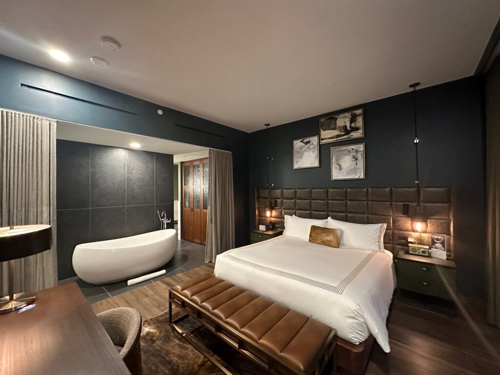 Hotel bedroom with dark blue walls and white bed.
