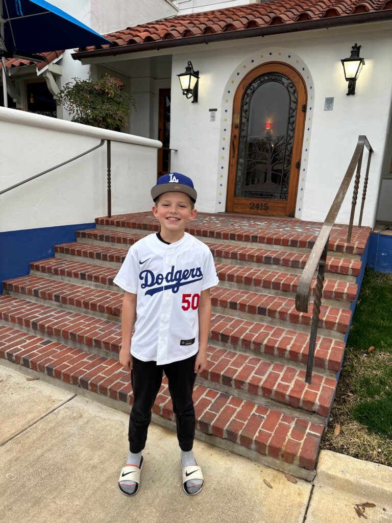 boy in white jersey and blue baseball hat