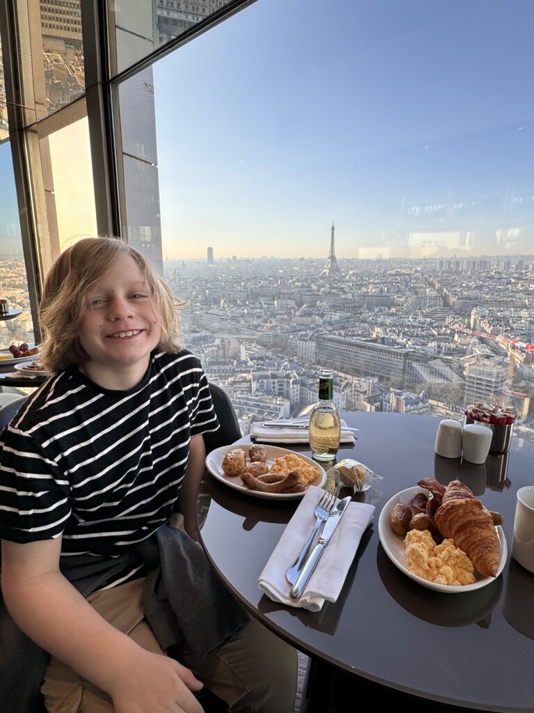 Boy eating breakfast with tower and city in background.