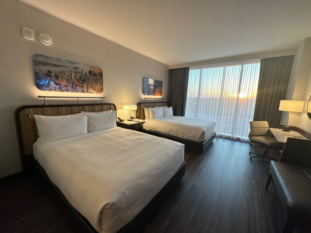 Hotel room with two queen beds with white duvets.