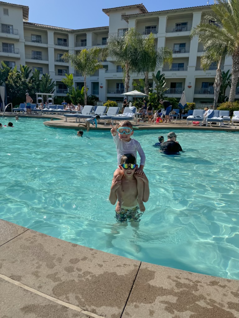 One boy on the shoulders of another boy in a pool