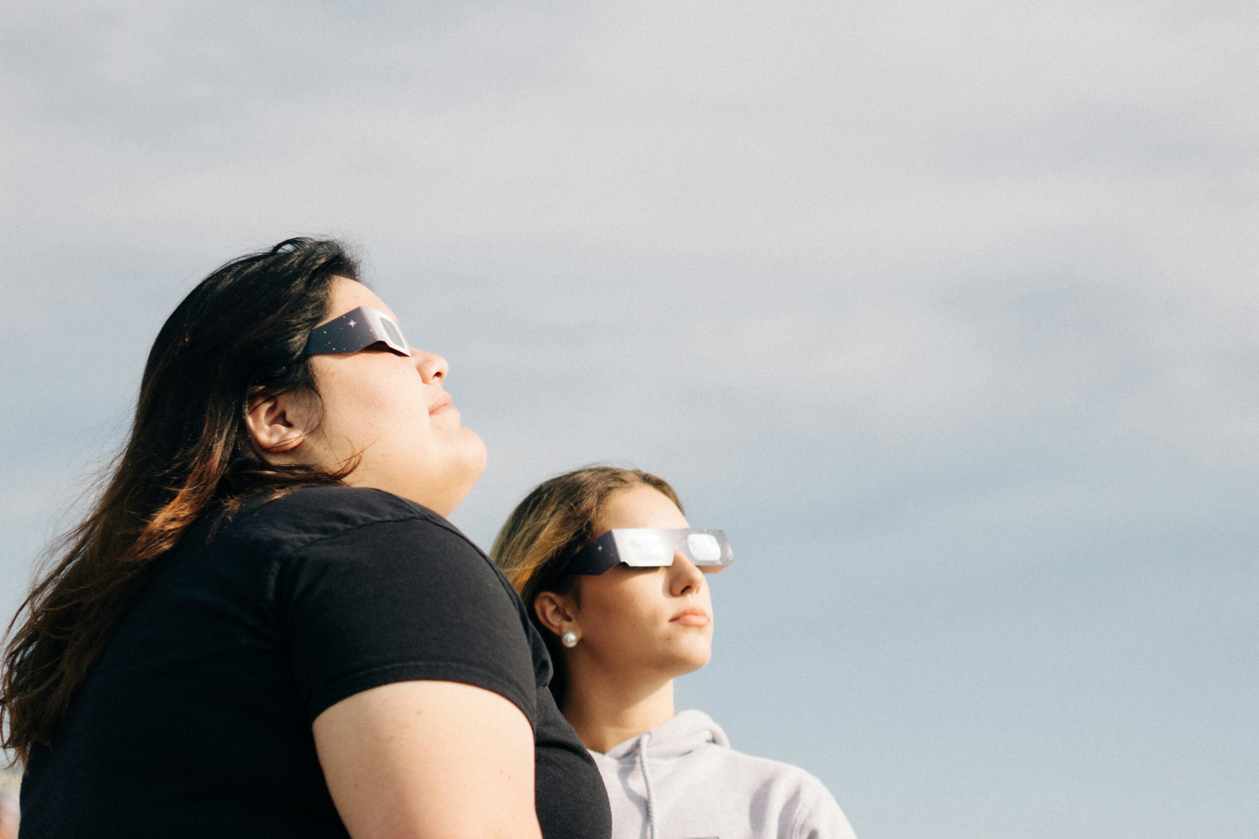 Two women watching solar eclipse with glasses on.