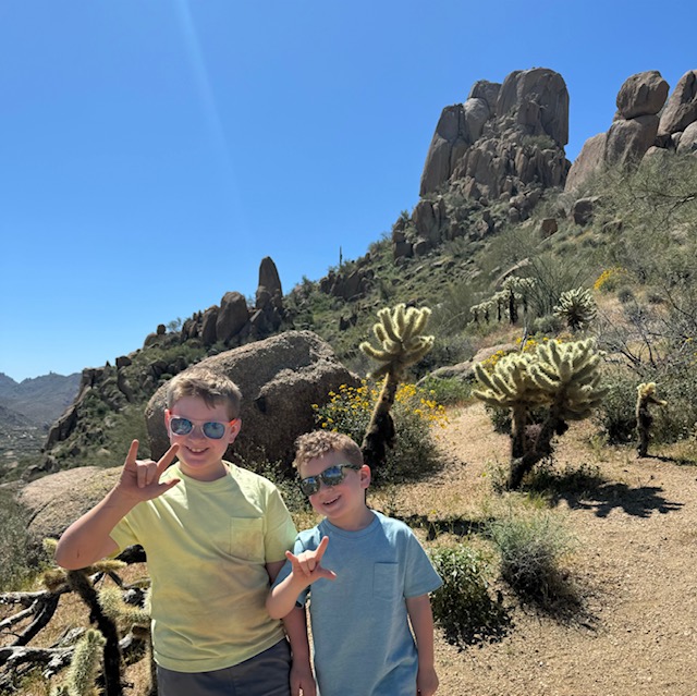 Two boys in desert with peace signs.