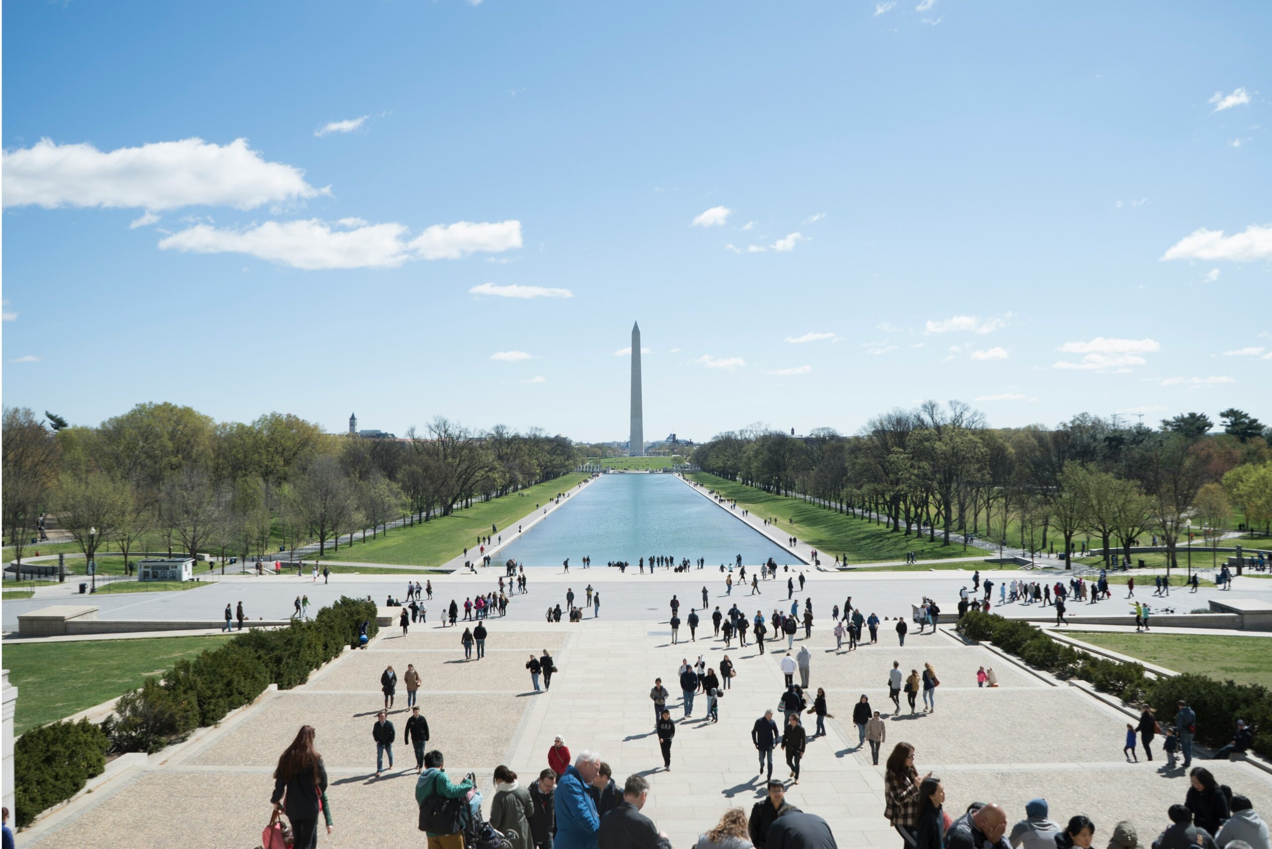 Large sphere monument in background with water in front of it and crowds heading there