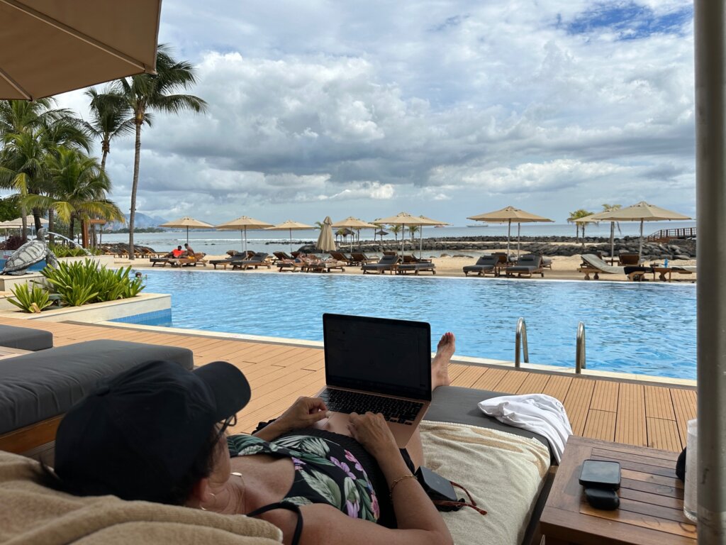 Woman working on computer by pool.