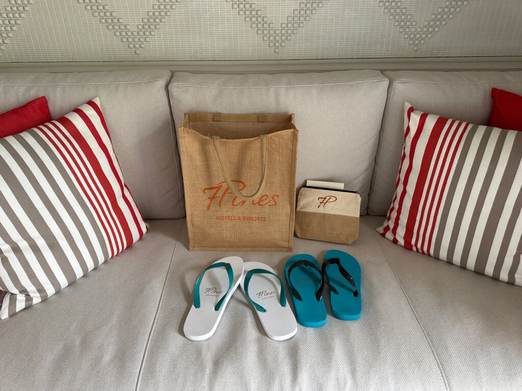 Sandals, beach bag and makeup bag on a white couch