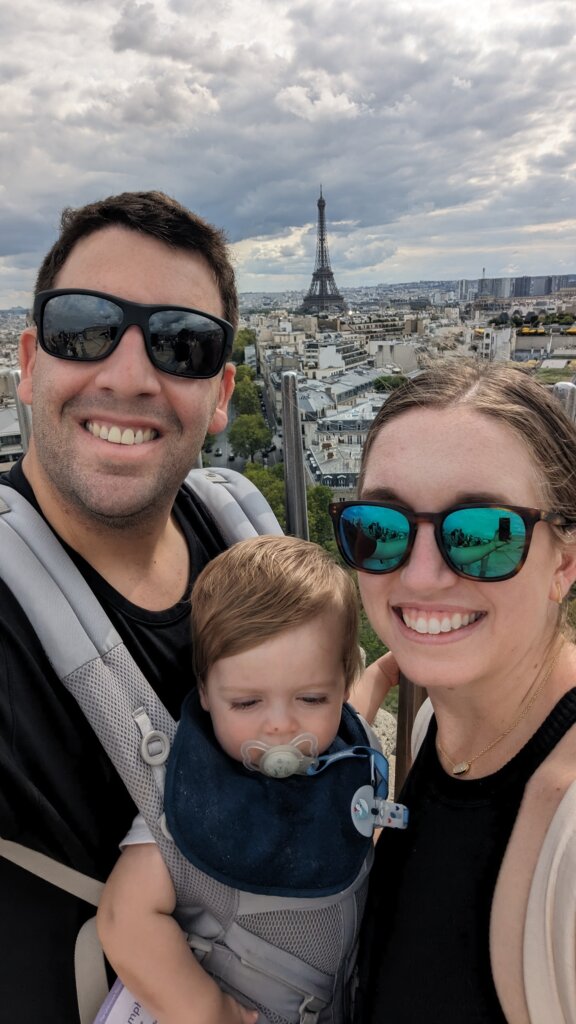 Man woman and child in front of city with large tower.