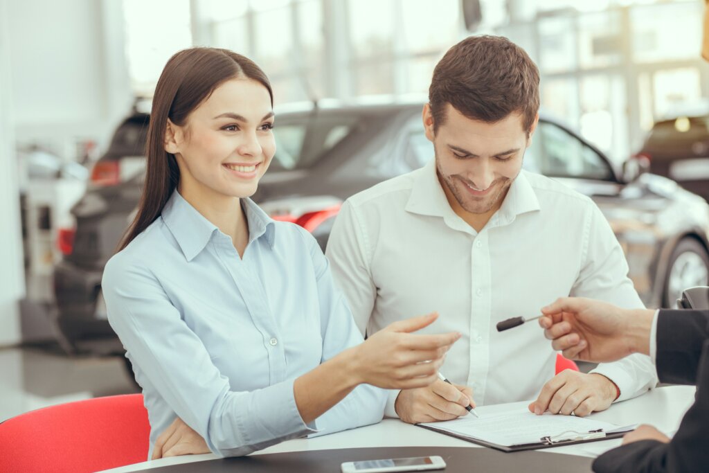 Man and woman getting a key in front of car