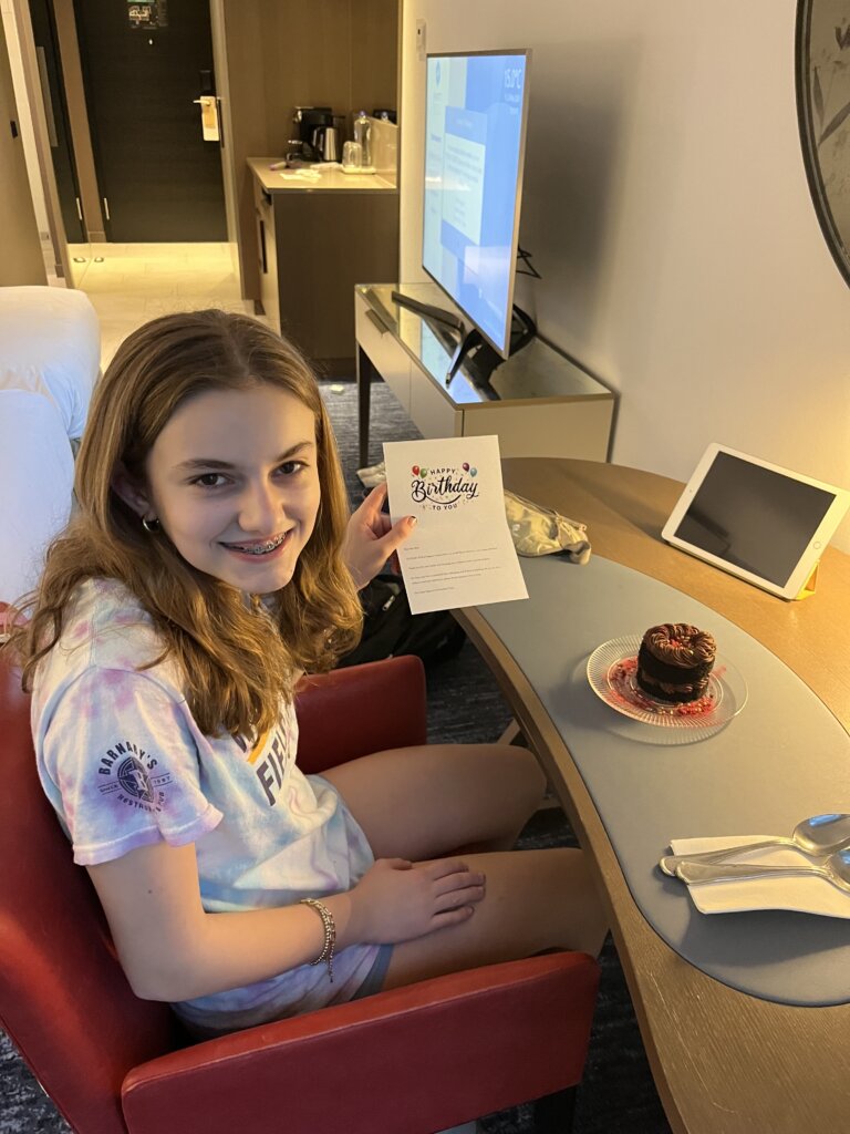 Girl holding birthday card by small cake.