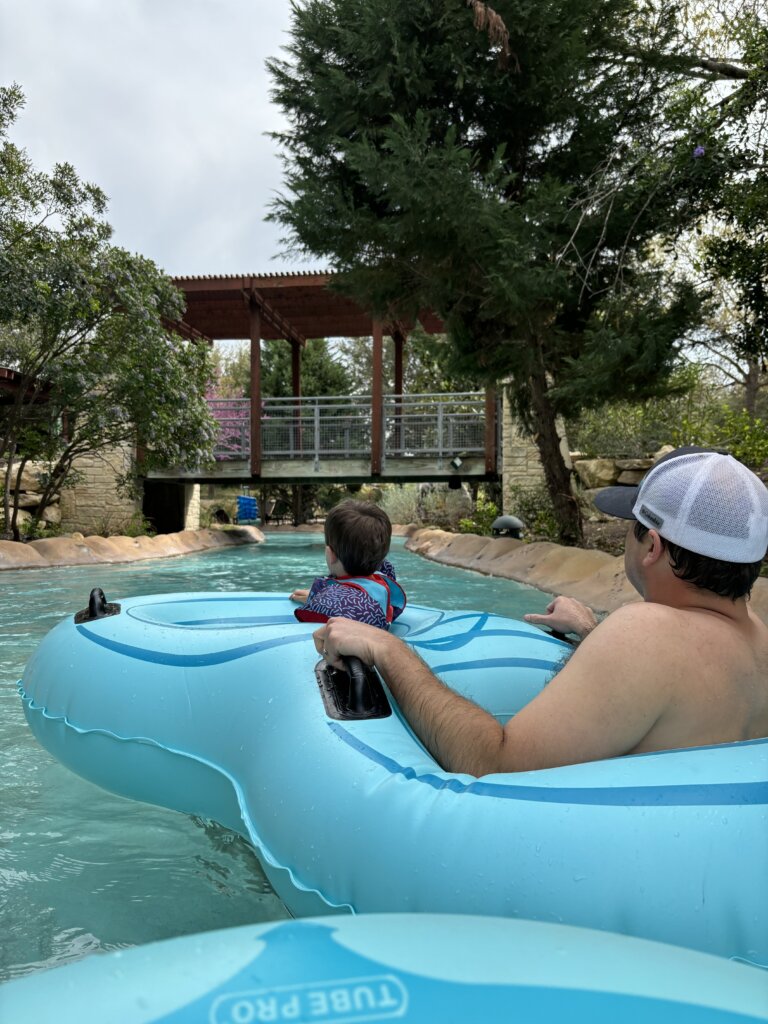 Man and boy on tube going on water.