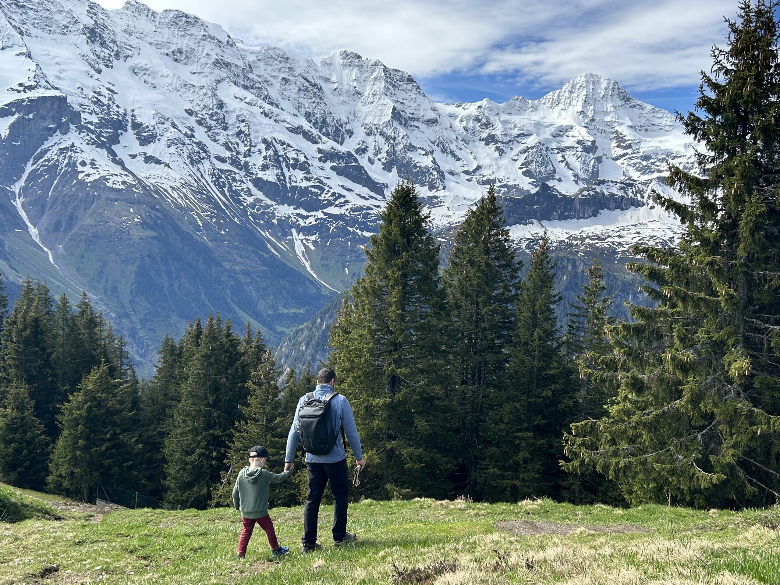 Man holding young girl's hand in front of snow capped mountains