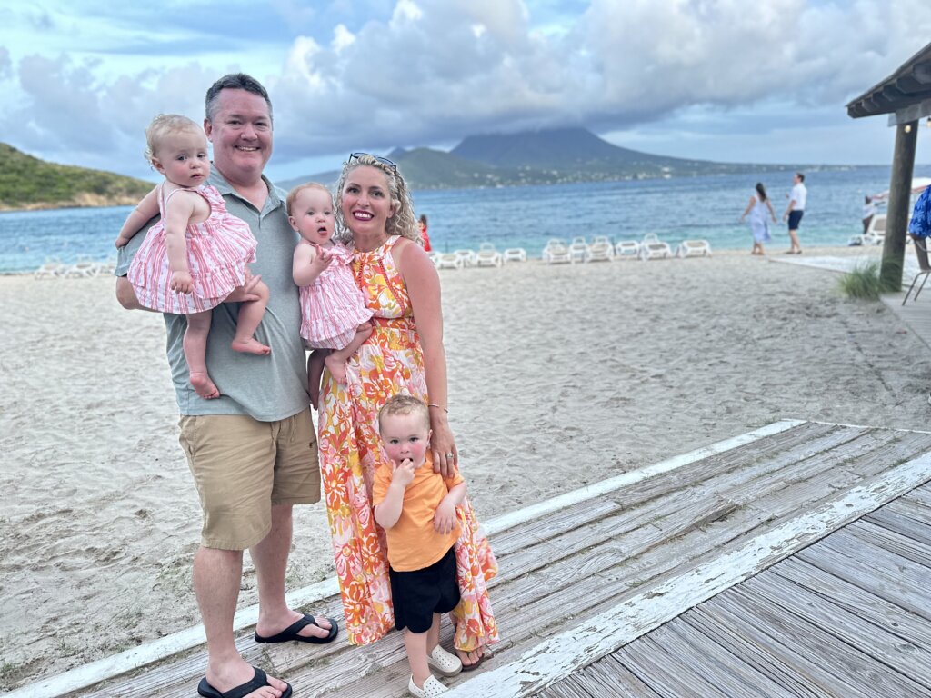 Man, woman, twin girls, and young boy near beach and blue water