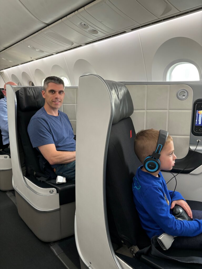 Man and young boy in business class seats on airplane