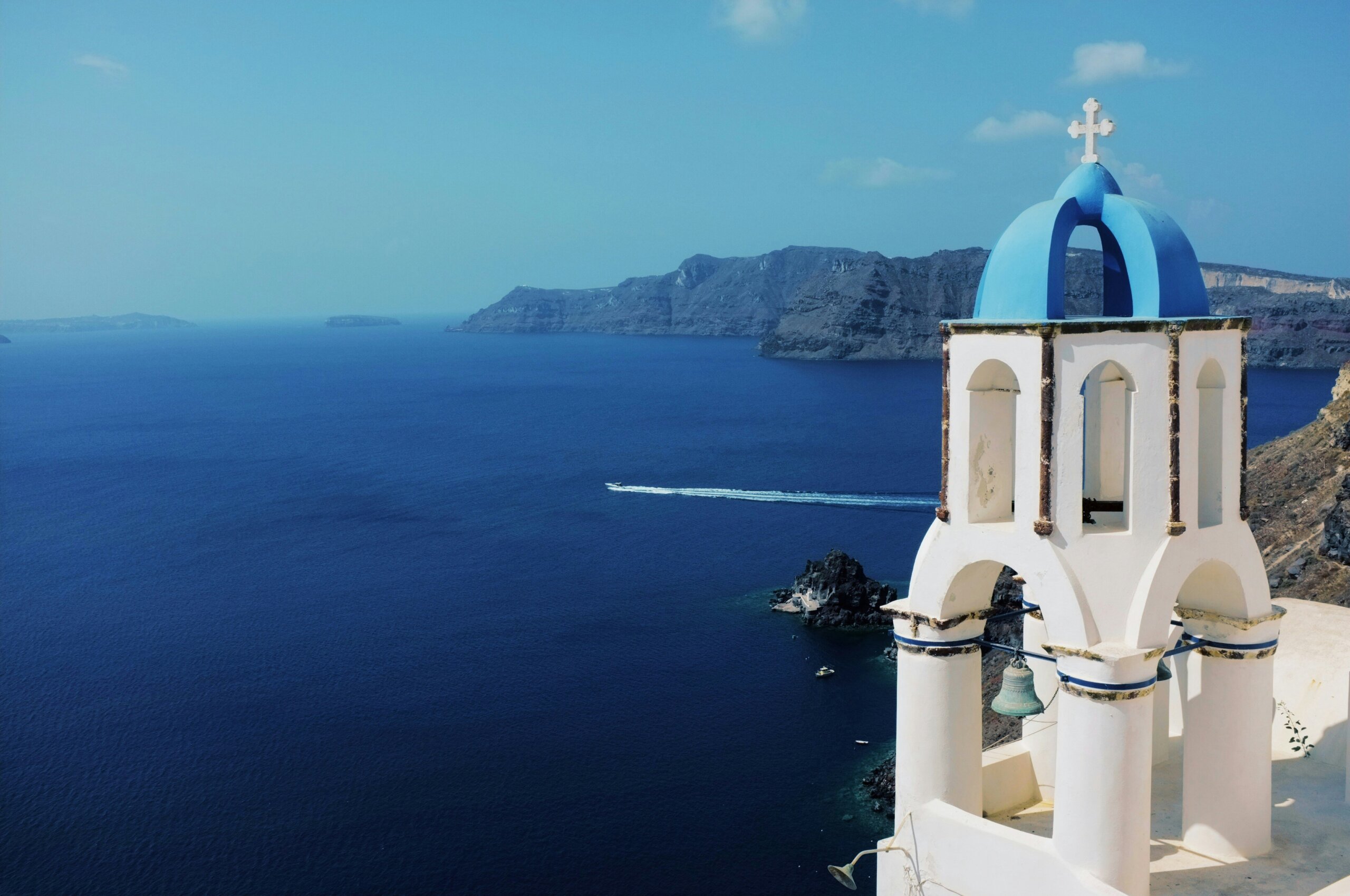 White tower with blue dome overlooking blue water